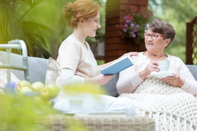 elder woman drinking tea while talking with caregiver