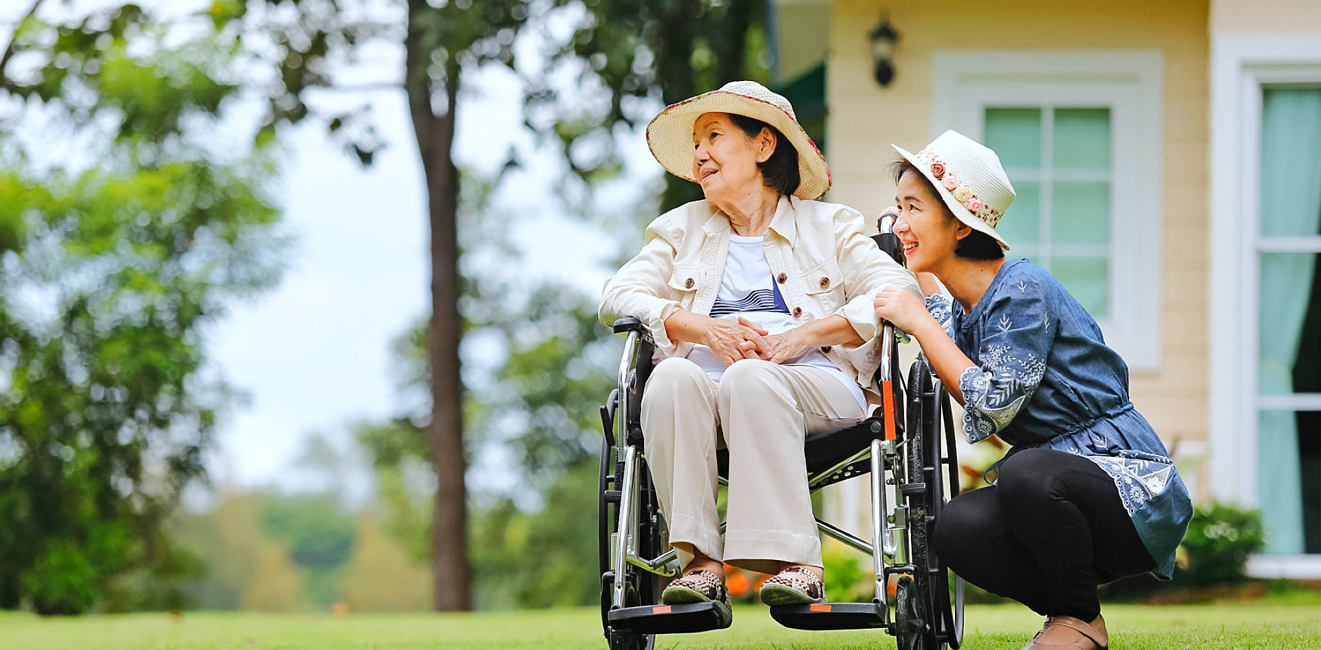 caregiver and senior woman on the wheelchair are looking outdoor